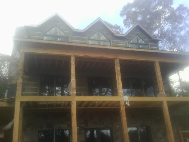 Dormers and porch framing on a large log home under construction — Roof Coating work by our crew in Fleming Island