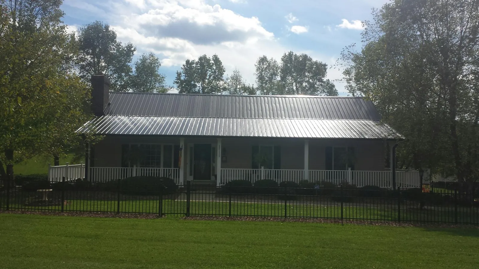 Gray metal roof on a brick ranch with a full width front porch — Gutter Guard Installation work by our crew in Fleming Island