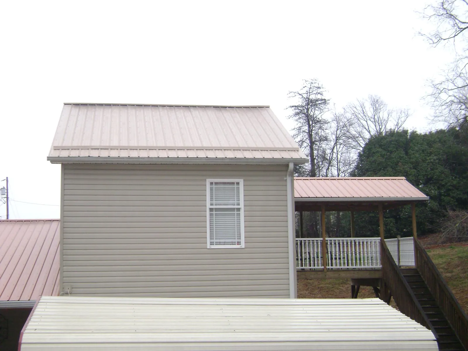 Tan metal roofs on a two story addition and attached porch, from a Roof Replacement job in Fleming Island