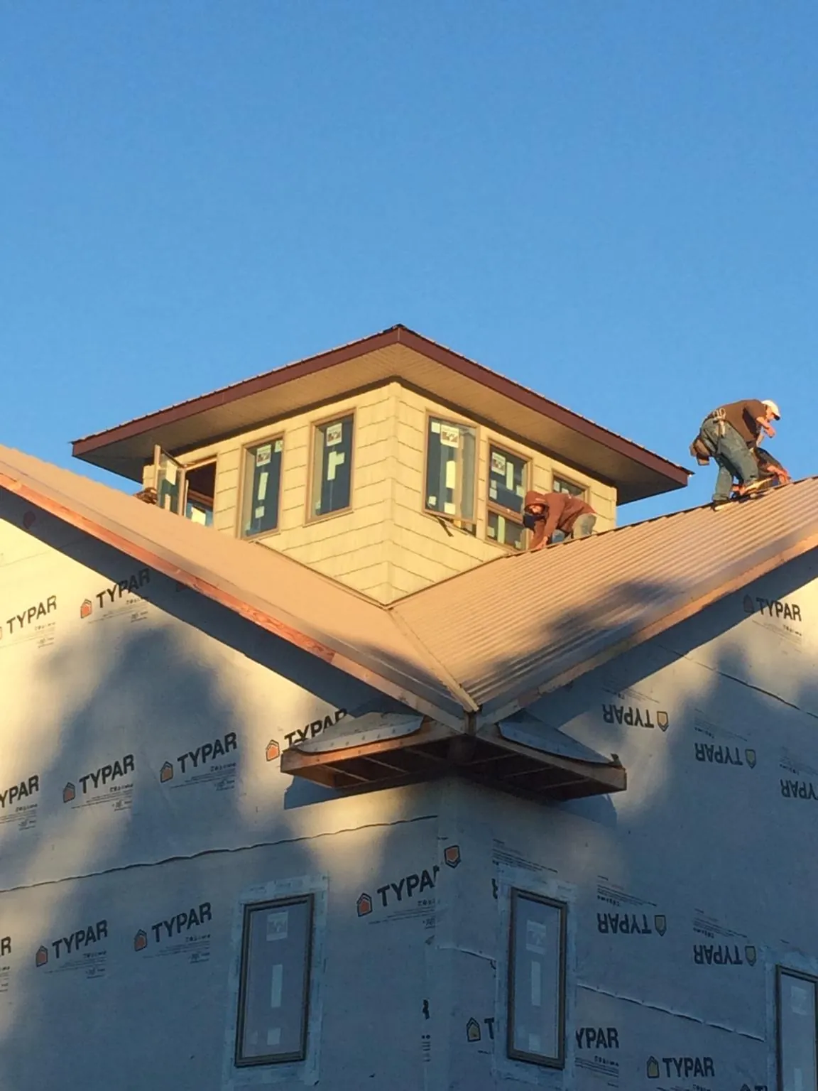 Roofers working around a rooftop cupola on a new metal roof at sunset — Roof Waterproofing in Fleming Island by Roofing Brothers